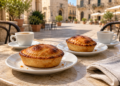 Two golden pasticciotti served with coffee at an outdoor café
